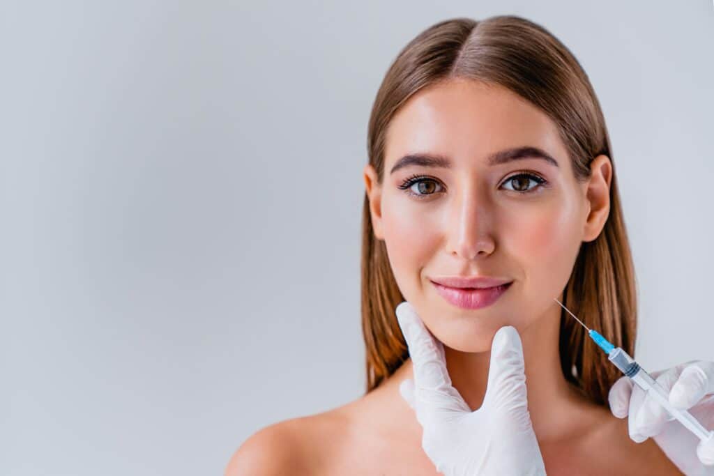 Woman’s face with the hands of a cosmetic dermatologist in Beverly Hills injecting cosmetic treatment.